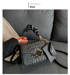 Close-up of black crocodile pattern faux leather handbag with pleated handle and gold hardware