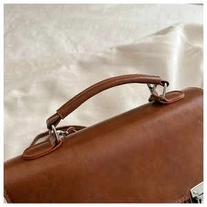 Gros plan d'un sac à main marron avec ferrures argentées et détails de texture du cuir