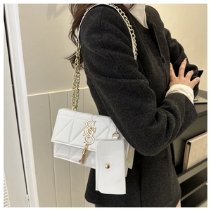 Detail of white quilted crossbody bag with golden chain strap and tassel charm