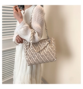 Detailed view of beige tote bag with brown geometric lattice pattern on a model shoulder