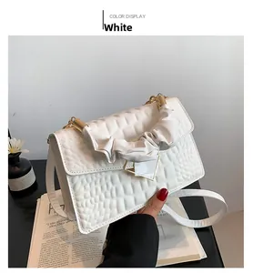 Close-up of white crocodile texture handbag with pleated handle and gold buckle detail