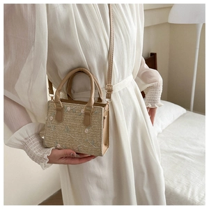 Close-up of woven straw handbag with floral embroidery and PU leather strap