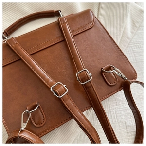 Détails des bretelles réglables et ferrures en métal argenté sur un sac en cuir marron