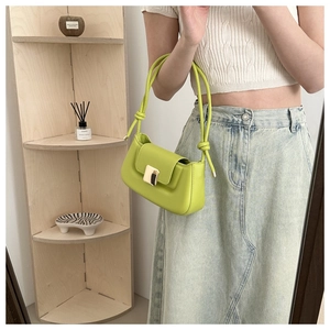Detail showing bright green leather shoulder bag with gold square buckle and knotted handle