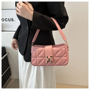 Detail of light pink quilted shoulder bag with golden H-buckle on a stylish model