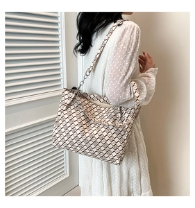 Detail of checkered tote bag with fashion logo print and metal chain leather strap