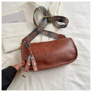 Detail of a brown cylindrical Boston bag with a wide geometric print shoulder strap
