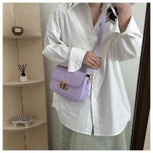Sac bandoulière en cuir lavande avec fermoir doré porté par un mannequin en décor épuré