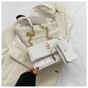 Detail of white quilted crossbody bag with golden metal S logo and tassel pendant