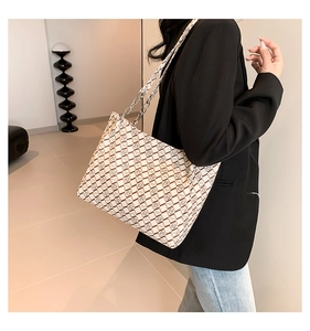 Detail of white tote bag with brown geometric patterns and silver chain leather strap
