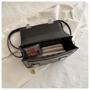 Vue intérieure d'un sac à bandoulière en cuir noir montrant l'espace de rangement chic