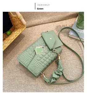 Detail of light green pleated handbag with crocodile pattern and square metal buckle