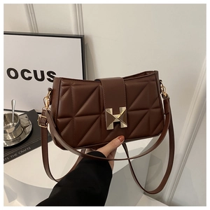Detail of dark brown quilted bag featuring a prominent gold H-shaped magnetic clasp closure