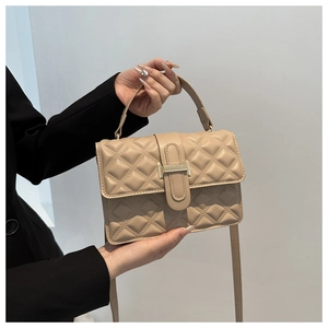 Close-up of beige quilted crossbody bag featuring elegant gold metal clasp and top handle