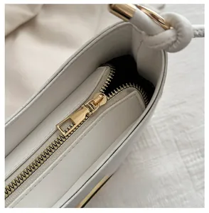 Detailed macro view of the smooth golden zipper and hardware on a cream leather handbag