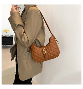 Detail of a brown quilted leather underarm bag with a vintage gold metal clasp accent