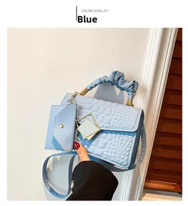 Detail of light blue faux crocodile skin handbag with pleated handle and mini purse