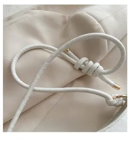 Detail of white leather handle with knot design and gold metal hardware on handbag
