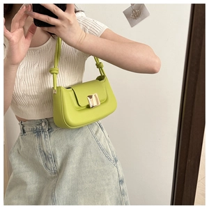 Detail of avocado green leather shoulder bag with gold clasp and knotted strap detail