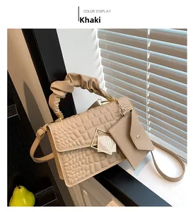Detail of khaki crocodile texture handbag with pleated handle and mini charm accessory