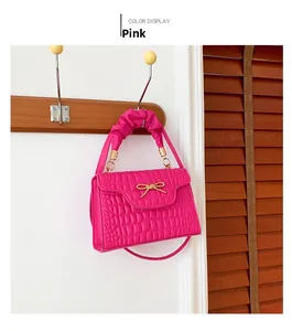 Detailed view of pink crocodile pattern crossbody bag with golden bow clasp