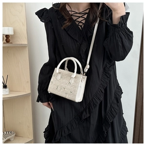 Detail of ivory woven handbag showing smooth round handle and adjustable leather shoulder strap
