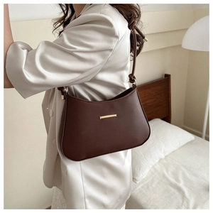 Detail view of a brown matte leather shoulder bag with sleek gold metal hardware