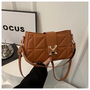 Close-up of caramel quilted crossbody bag featuring a golden H-shaped metal buckle detail