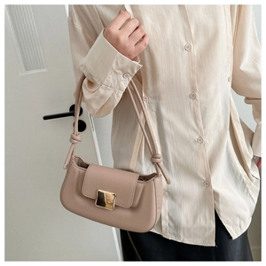 Detail of beige underarm bag featuring a golden square buckle and elegant knotted strap