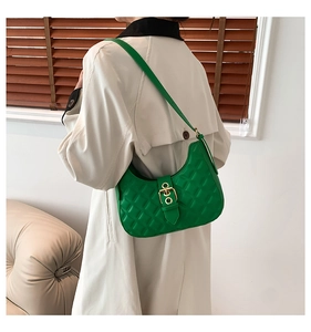 Detail of a bright green quilted crescent shoulder bag showing gold metal buckles