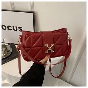Close-up of red quilted leather handbag featuring a golden H-shaped metal buckle detail