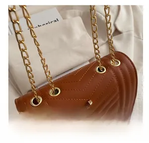 Detail of brown V-quilted leather handbag with golden chain straps and metallic eyelets