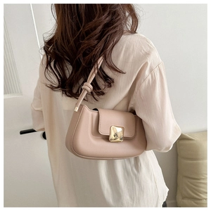 Elegant beige leather shoulder bag with a gold buckle and knotted strap on model