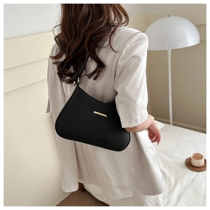 Minimalist black matte leather hobo bag with gold metal buckle shown on model shoulder