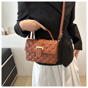 Detail of reddish-brown quilted handbag with golden H-shaped hardware on a model
