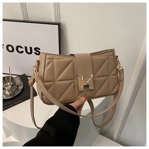 Detail of beige quilted crossbody bag featuring a signature gold-tone H buckle closure