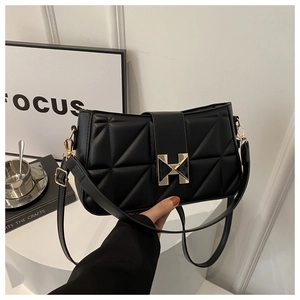 Detailed close-up of a black quilted leather handbag featuring a gold H-shaped clasp