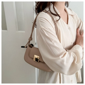 Detail view of apricot faux leather underarm bag featuring a gold buckle and knotted strap