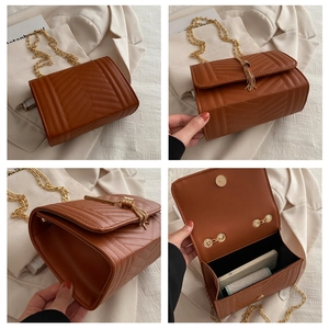Detail view of caramel brown crossbody bag with chevron quilting and gold chain tassels