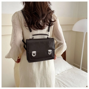 Sac à dos rétro en cuir marron foncé porté sur le dos dans une chambre cosy