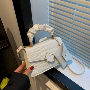 White crocodile embossed handbag with cloud handle and mini pouch in soft window light