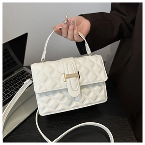 Detailed view of white quilted crossbody bag with gold square lock and top handle grip