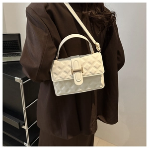 Chic white quilted shoulder bag with gold metal H buckle worn on a brown blazer