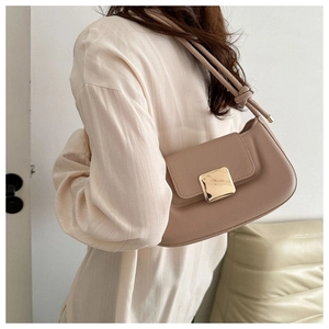 Detail of beige leather baguette bag featuring golden buckle and knotted shoulder strap