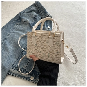 Close-up of woven straw handbag with floral embroidery and adjustable leather strap