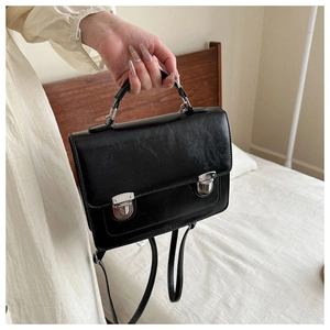 Détail du sac vintage noir avec boucles en métal argenté et bretelles doubles