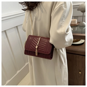 Detail of burgundy chevron quilted bag with gold tassel and elegant chain strap