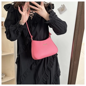 Detailed view of pink leather shoulder bag with gold metal trim and slim strap detail
