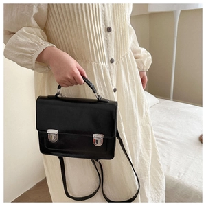 Classic black leather crossbody bag with silver buckles shown on a model in a dress