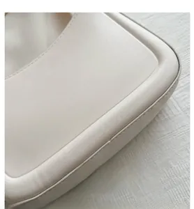 Detailed view of cream leather shoulder bag showcasing fine stitching and smooth matte texture